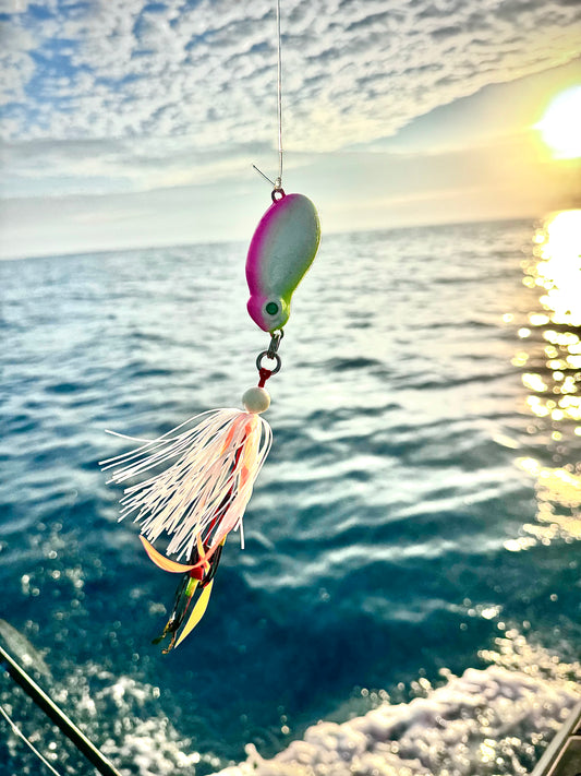 Frothy Okky jig in pink and glow hanging over blue water at sunset