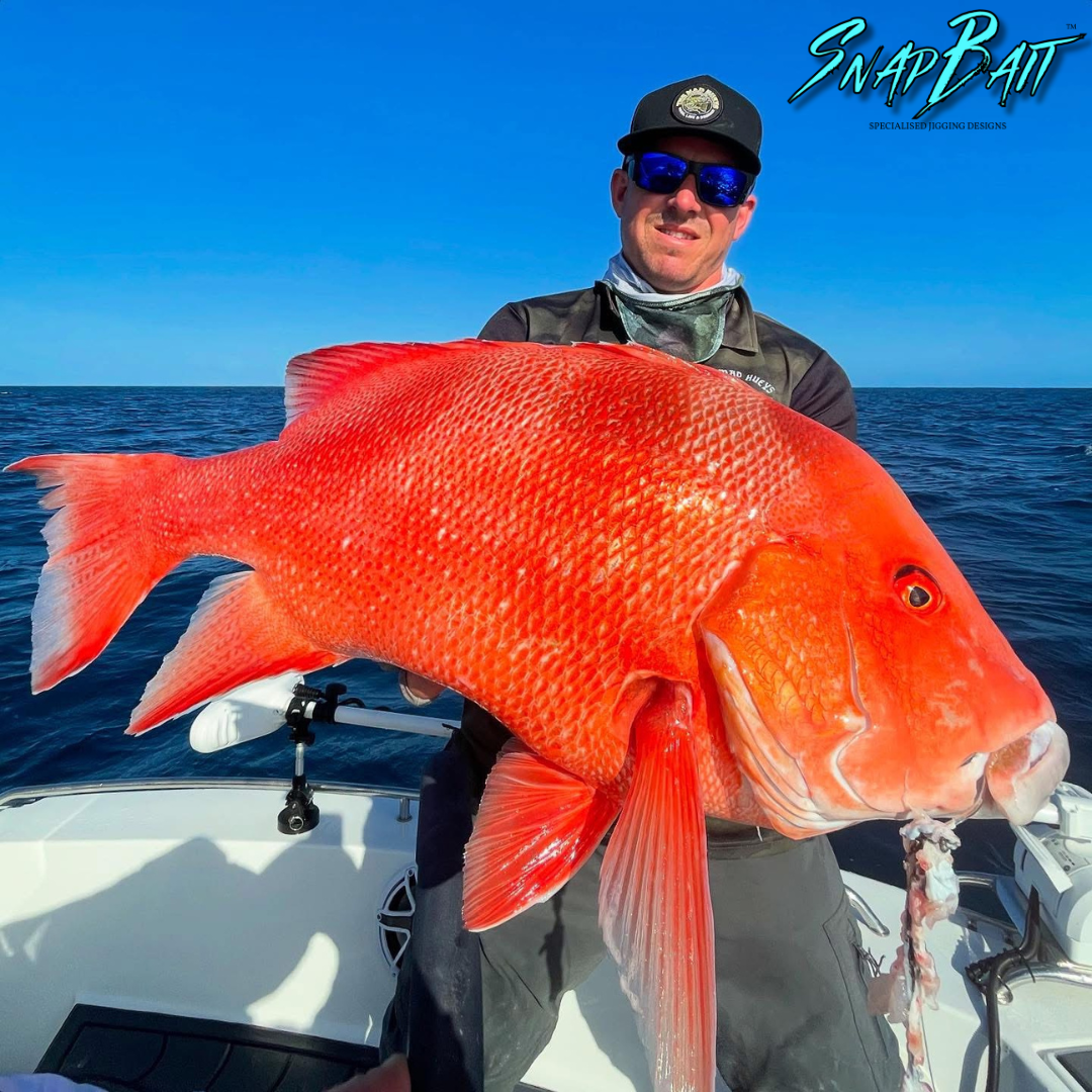 Angler on a boat holding a large red reef fish caught on a Triple Threat jig
