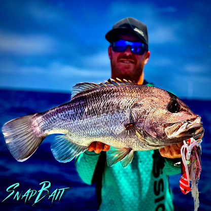 SnapBait Australia Hybrid Jigs caught large fish held by angler wearing sunglasses on ocean background
